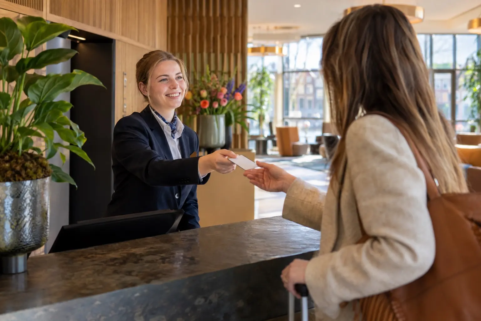 Hotelreceptioniste geeft een gast de kamersleutel